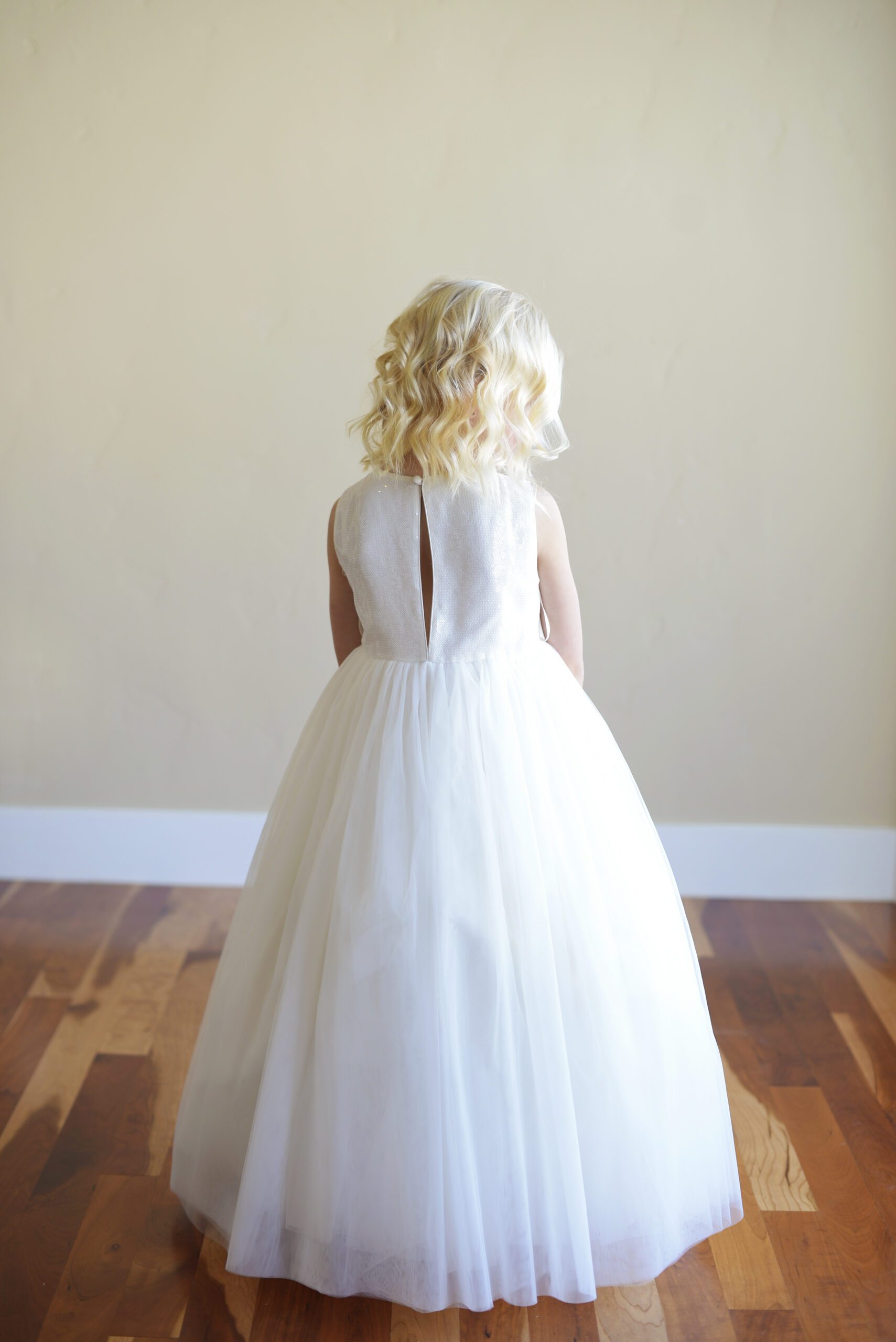 A photo of a flower girl wearing a ivory sequin dress with full tulle skirt