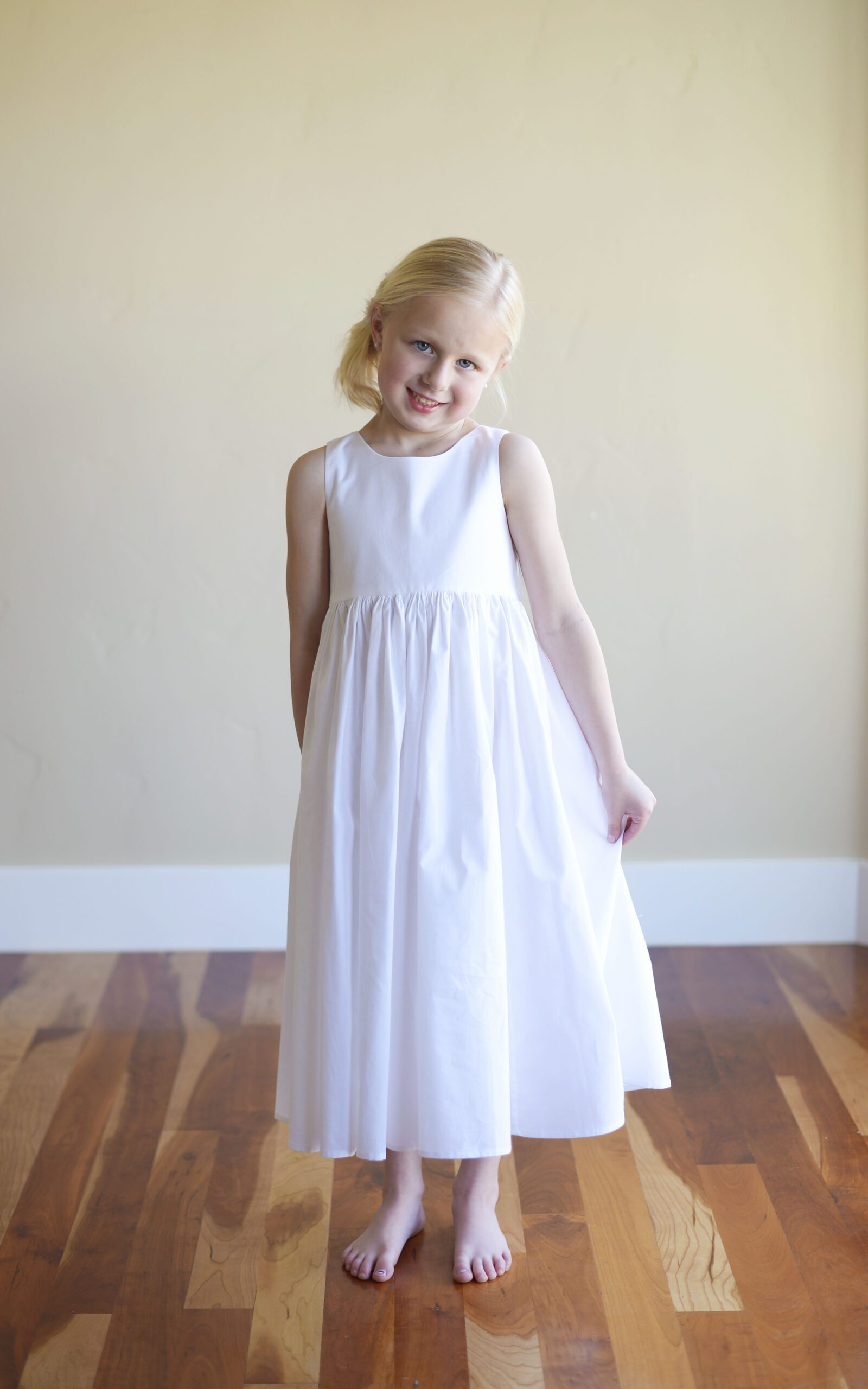 A photo of a flower girl wearing a simple cotton flower girl dress in white
