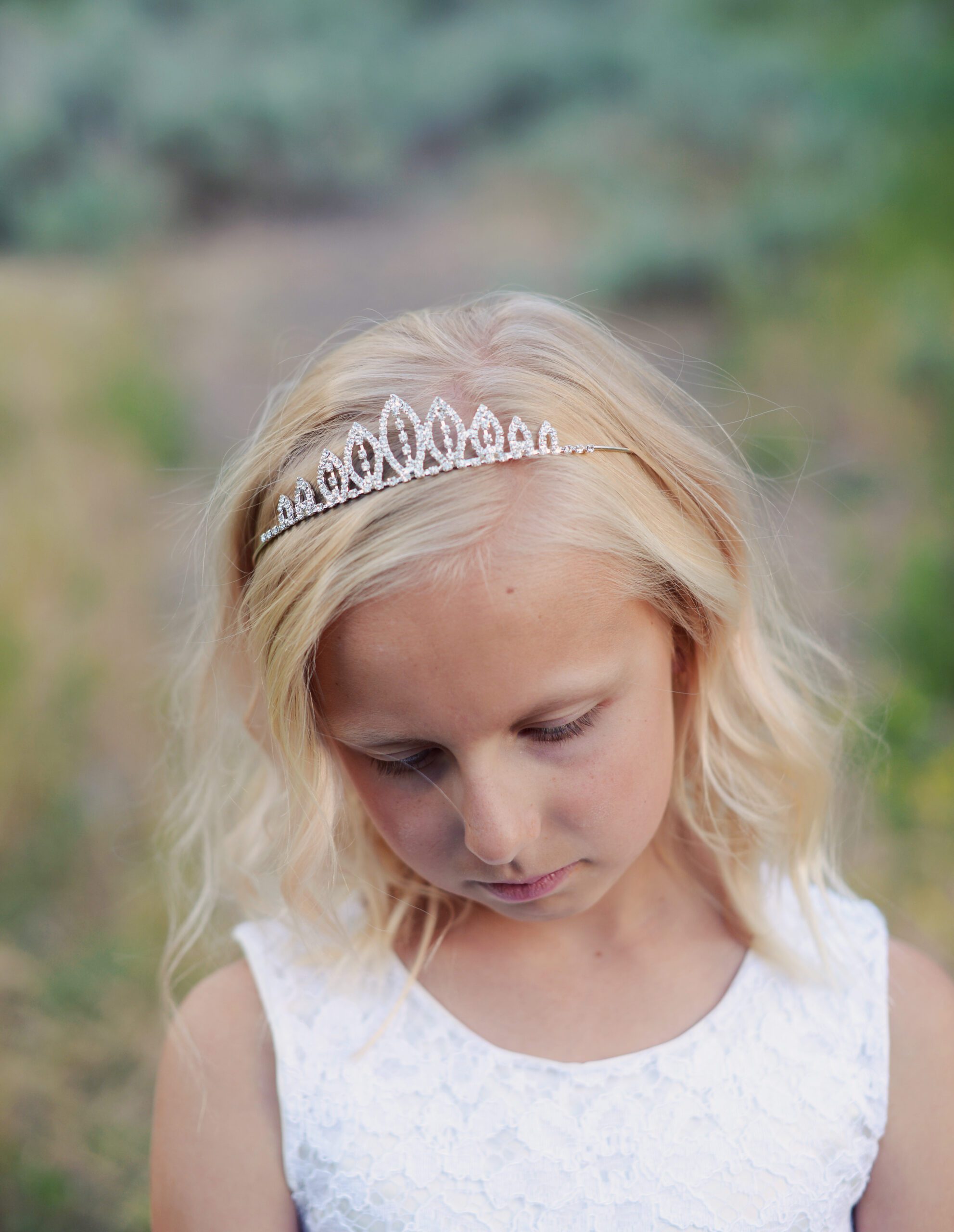 A photo of a flower girl wearing an ivory tulle dress and a rhinestone tiara