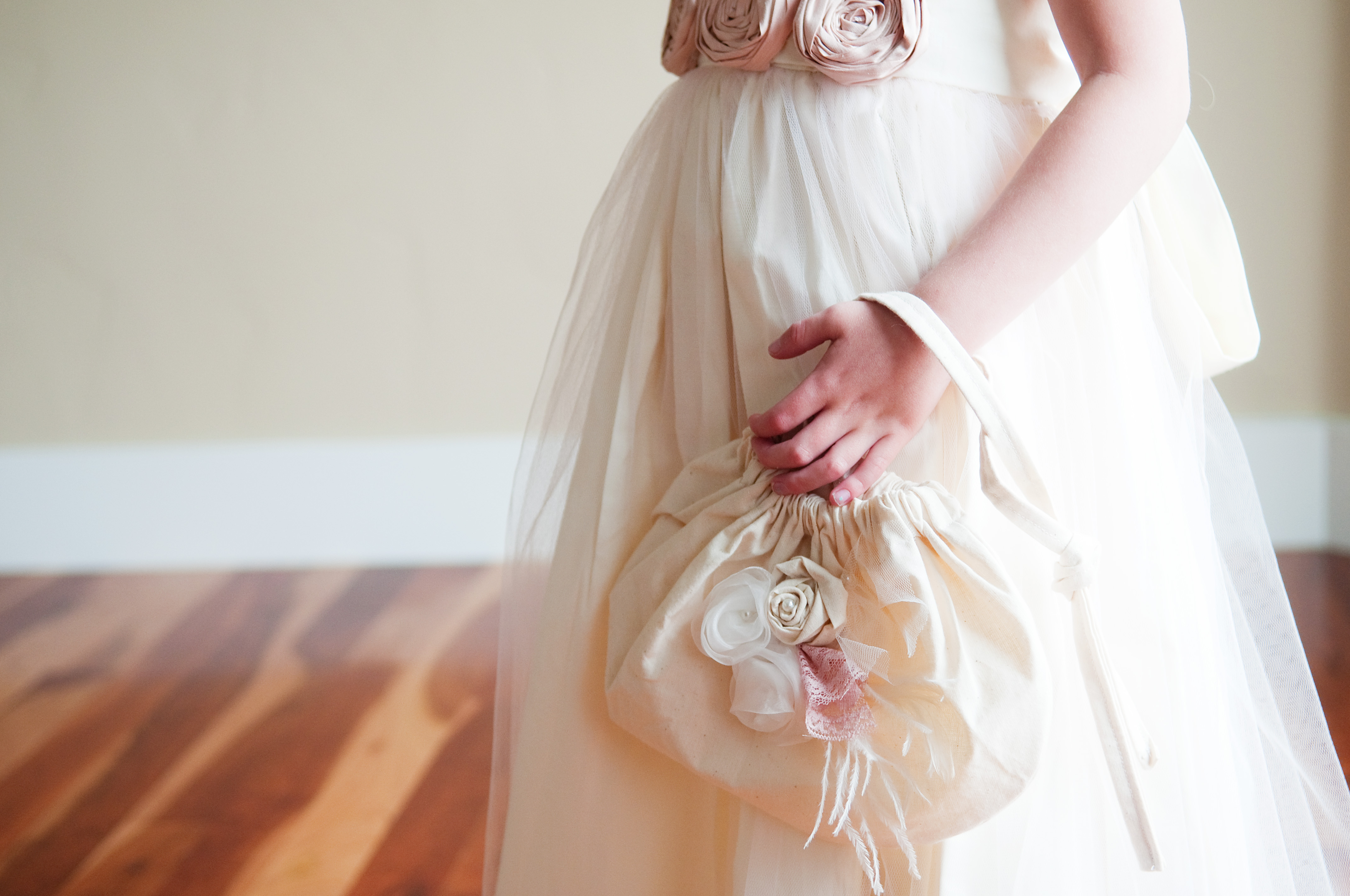 A photo of an ivory flower girl dress with a cotton drawstring bag with pink flowers
