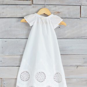 A photo of a white cotton christening gown with pretty lace detail at the hem