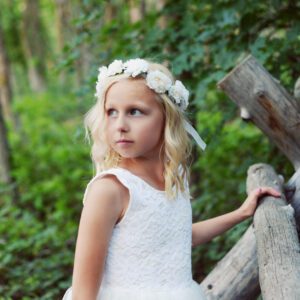 A photo of a flower girl wearing a white rose hair crown