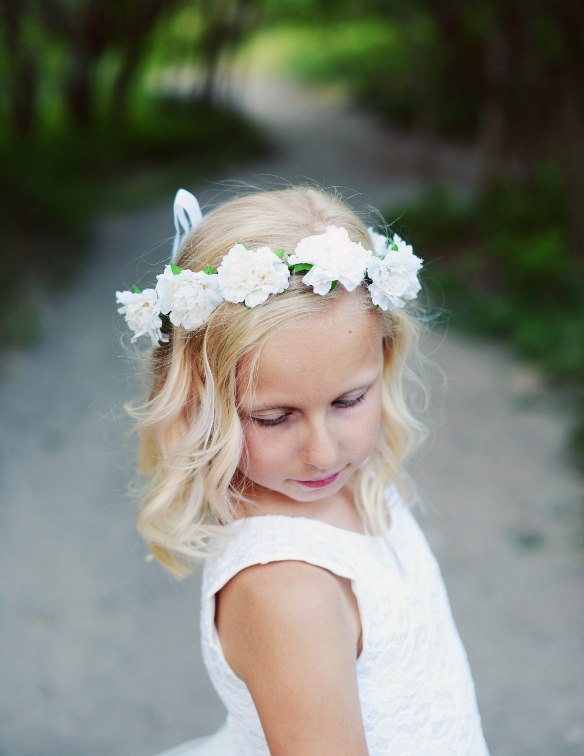 A photo of a flower girl wearing a white rose hair crown