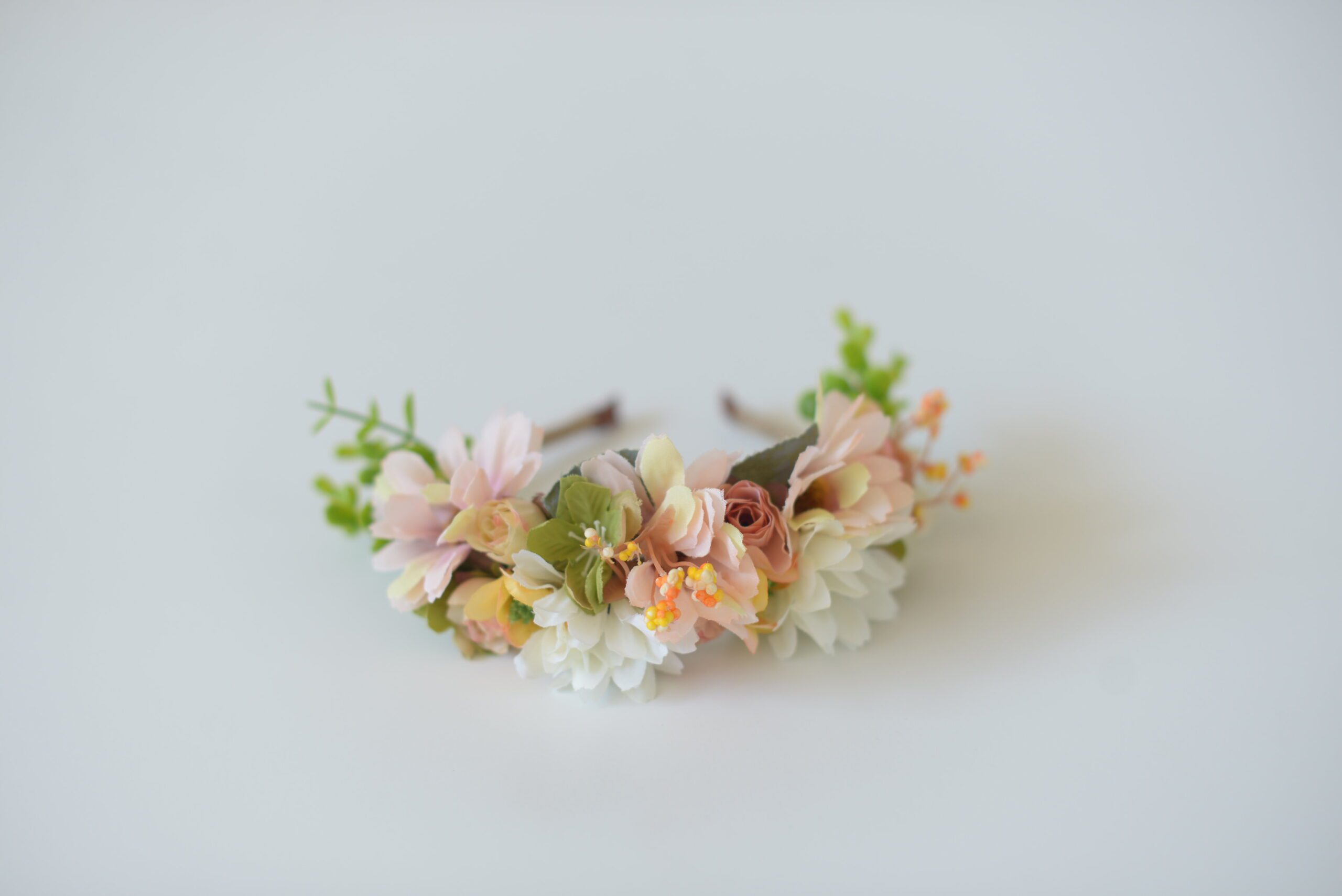 A photo of a floral flower girl headband in peach colours