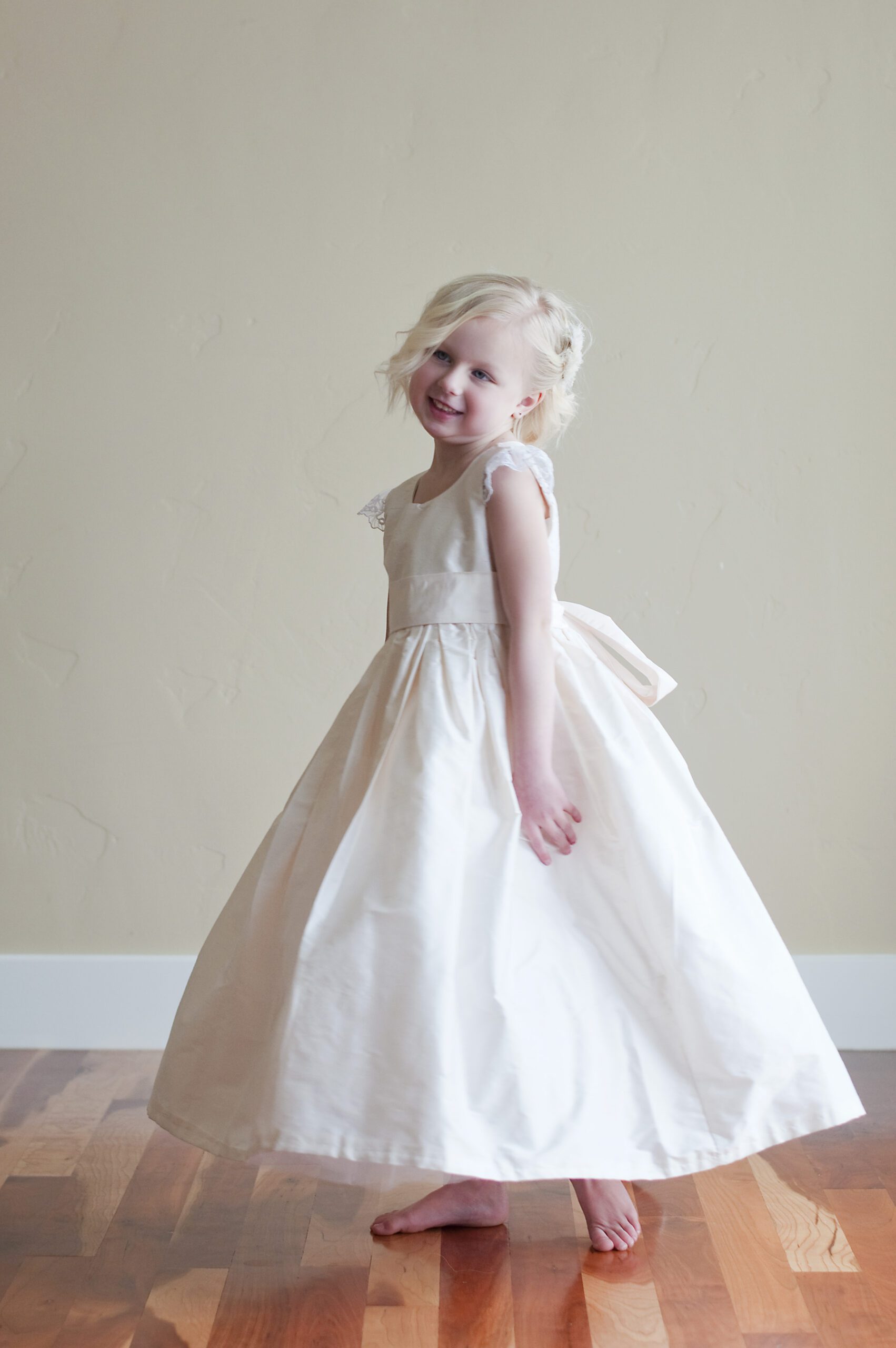 A photo of a blush pink flower girl dress with lace sleeves.