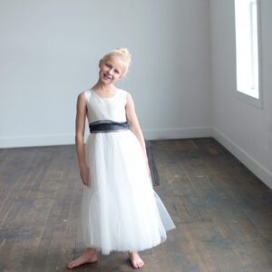 A photo of a flower girl wearing a silk and tulle skirt with a black organza skirt