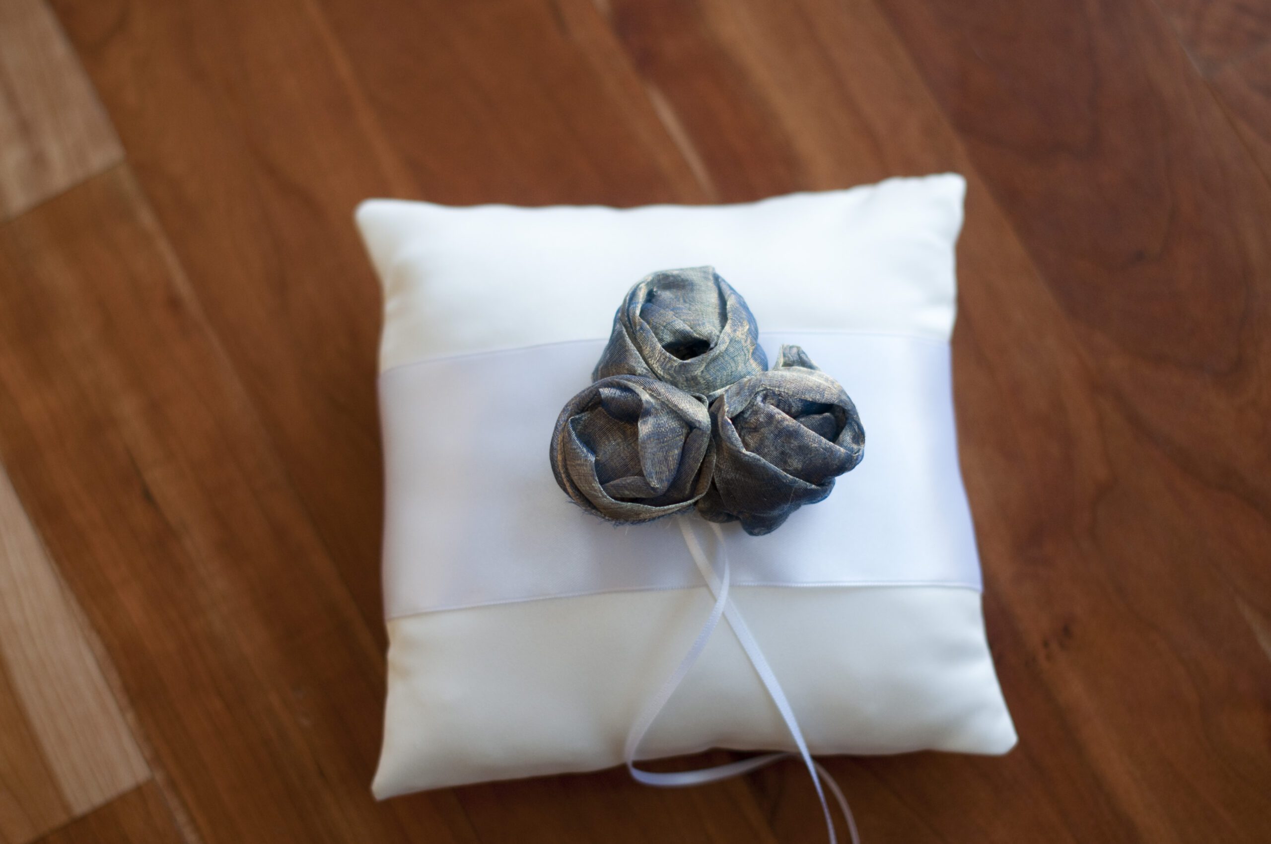 A photo of a cotton ring pillow with an over sized flower and. ribbon with diamante