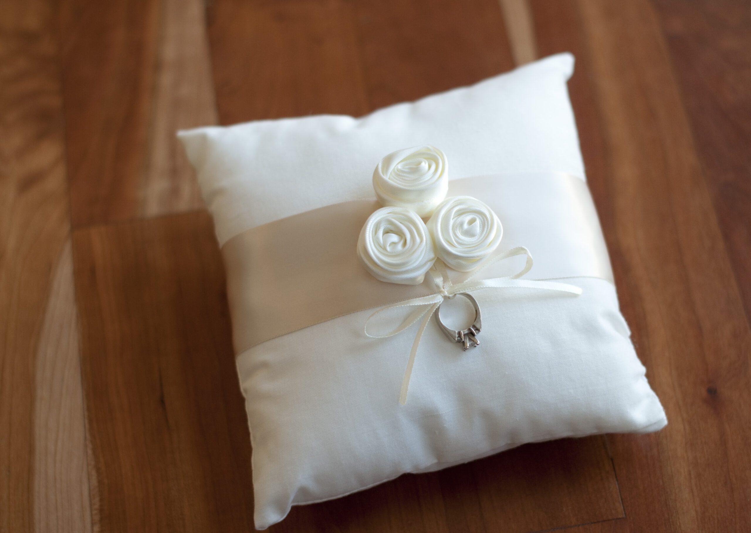 A photo of a cotton ring pillow with flowers and a ribbon