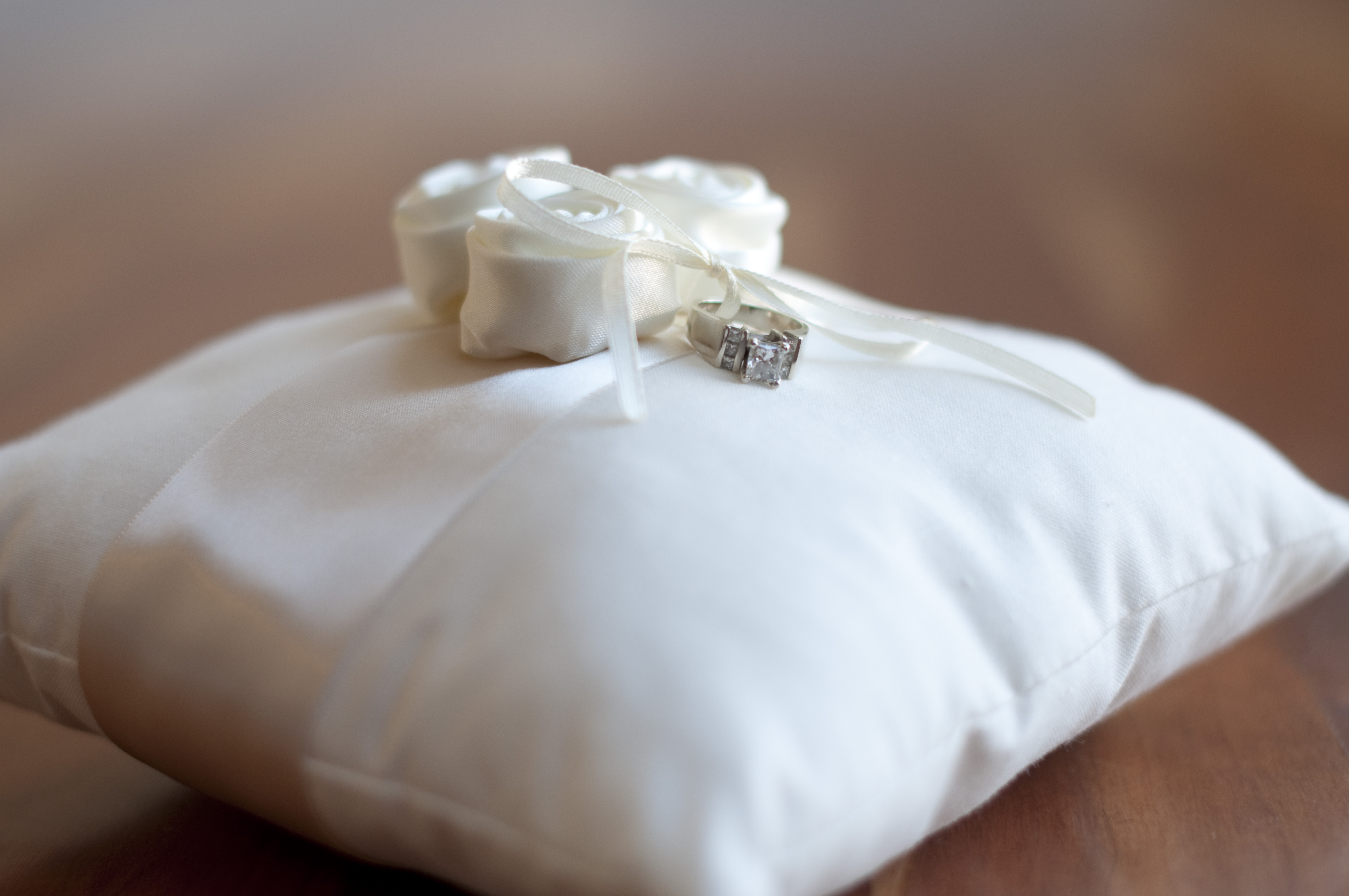 A photo of a cotton ring pillow with flowers and a ribbon ebellishment