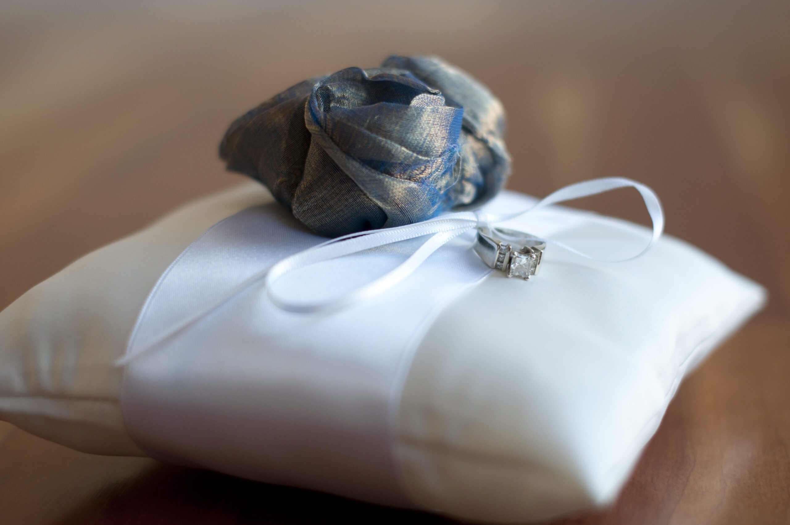A photo of a cotton ring pillow with an over sized flower and. ribn with diamante