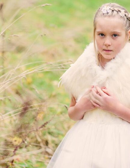 A photo of a girl wearing a featherer flower girl shawl in ivory