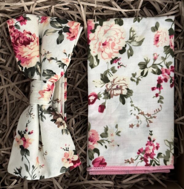A photo of a pink floral bow tie and pocket square on an ivory background ideal for weddings