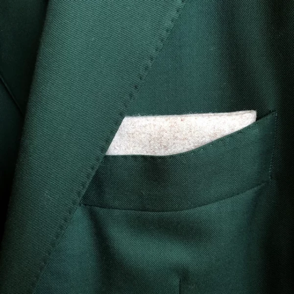 Cream wool pocket square worn with a dark green suit.