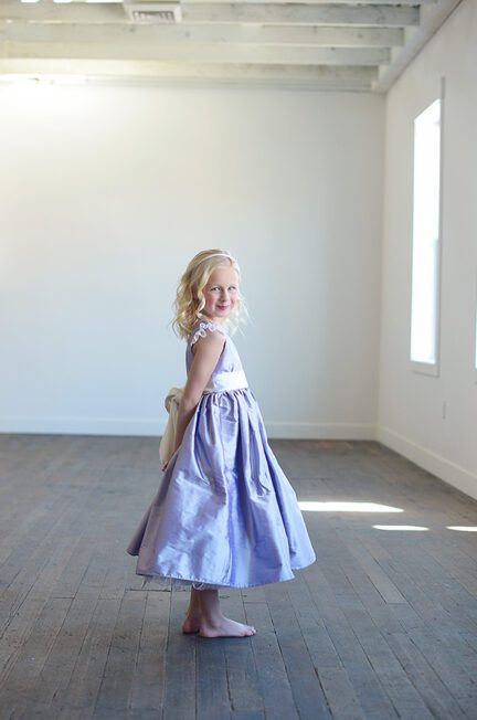 A photo of a purple silk flower girl dress with an ivory sash