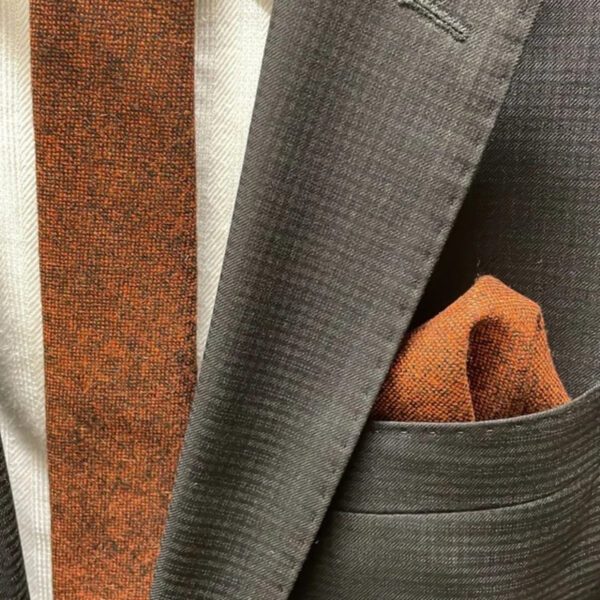 A photo of a burnt orange men's wool tie and pocket square