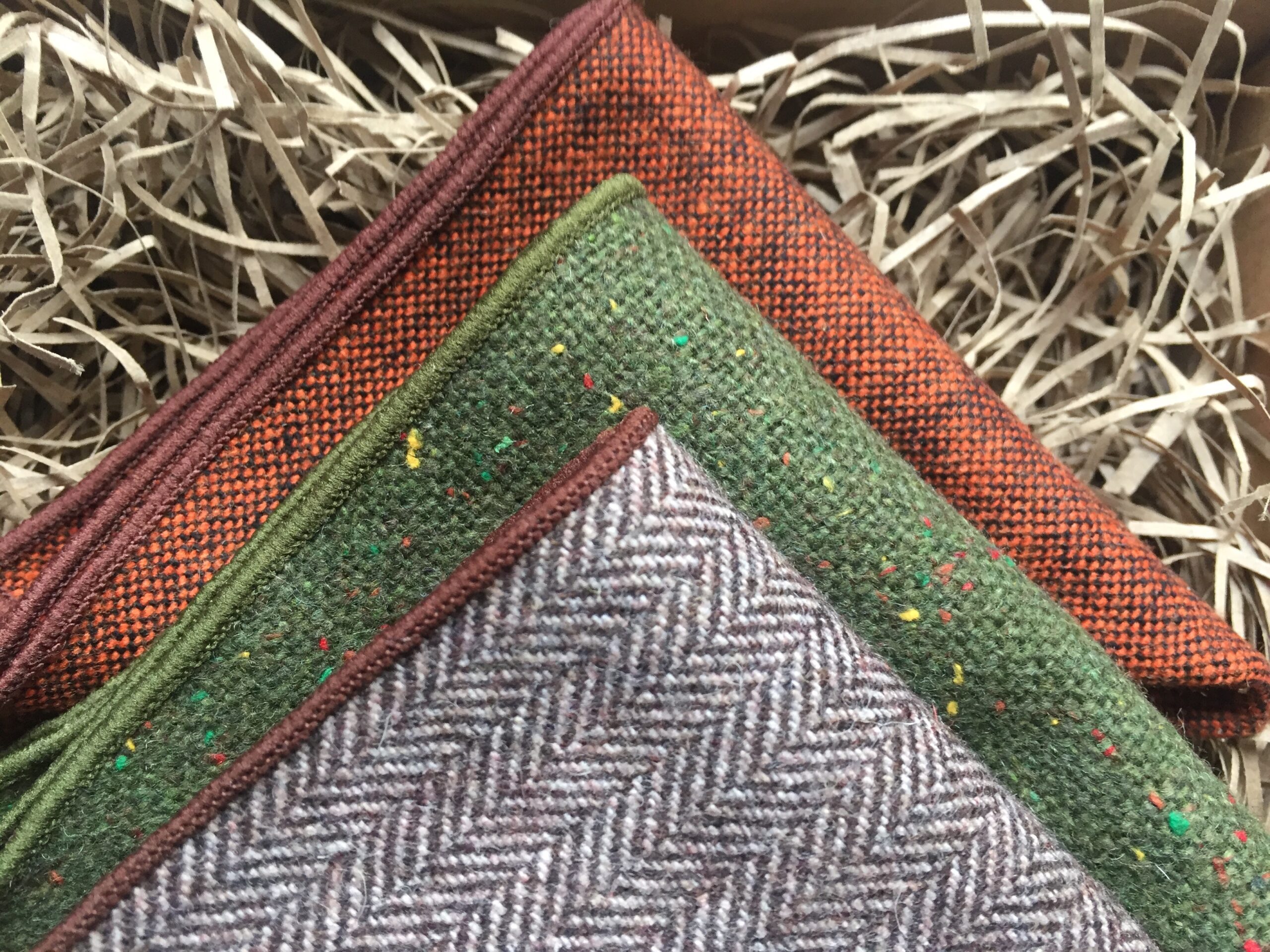 A photo of a trio of pocket squares in wool. This is a perfect man's gift. The pocket squares are made in wool and are in green, burnt orange and brown 
