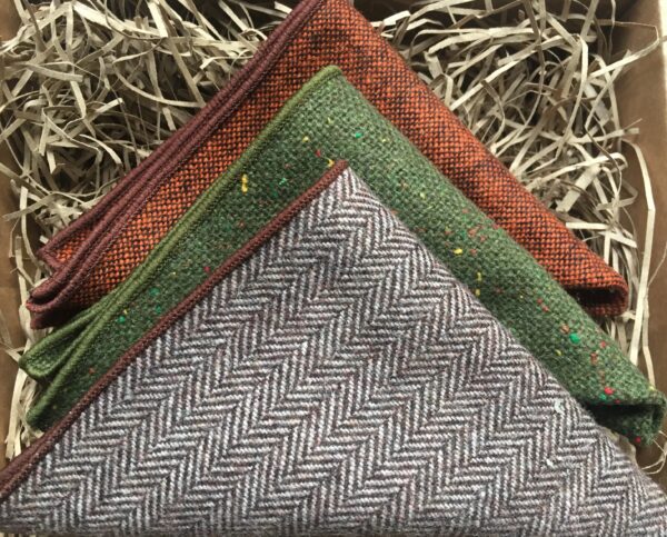 A photo of three wool pocket squares in brown, burnt orange and green