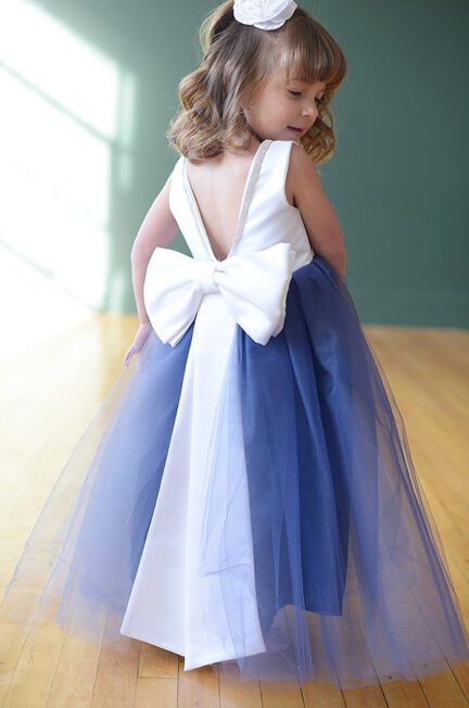 A photo fo a 4 year old flower girl wearing a white satin dress with a royal blue tulle skirt