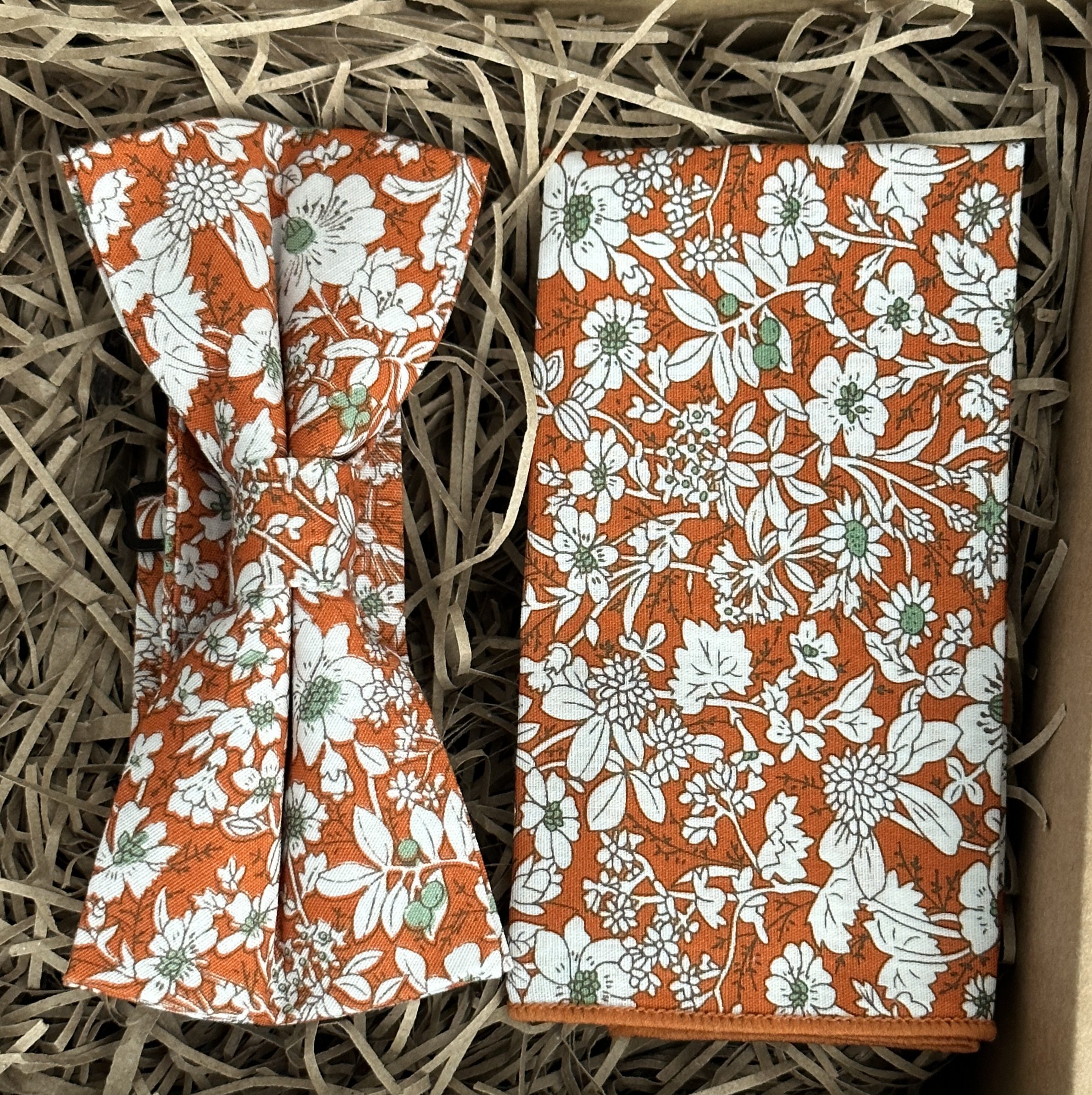 A photo of an orange floral bow tie and pocket square