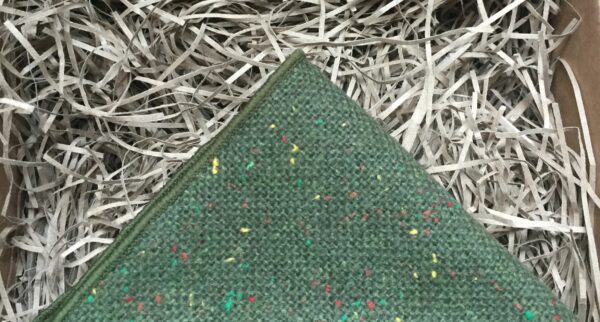 A photo of a moss greenc wool pocket square with coloured flecks in the wool
