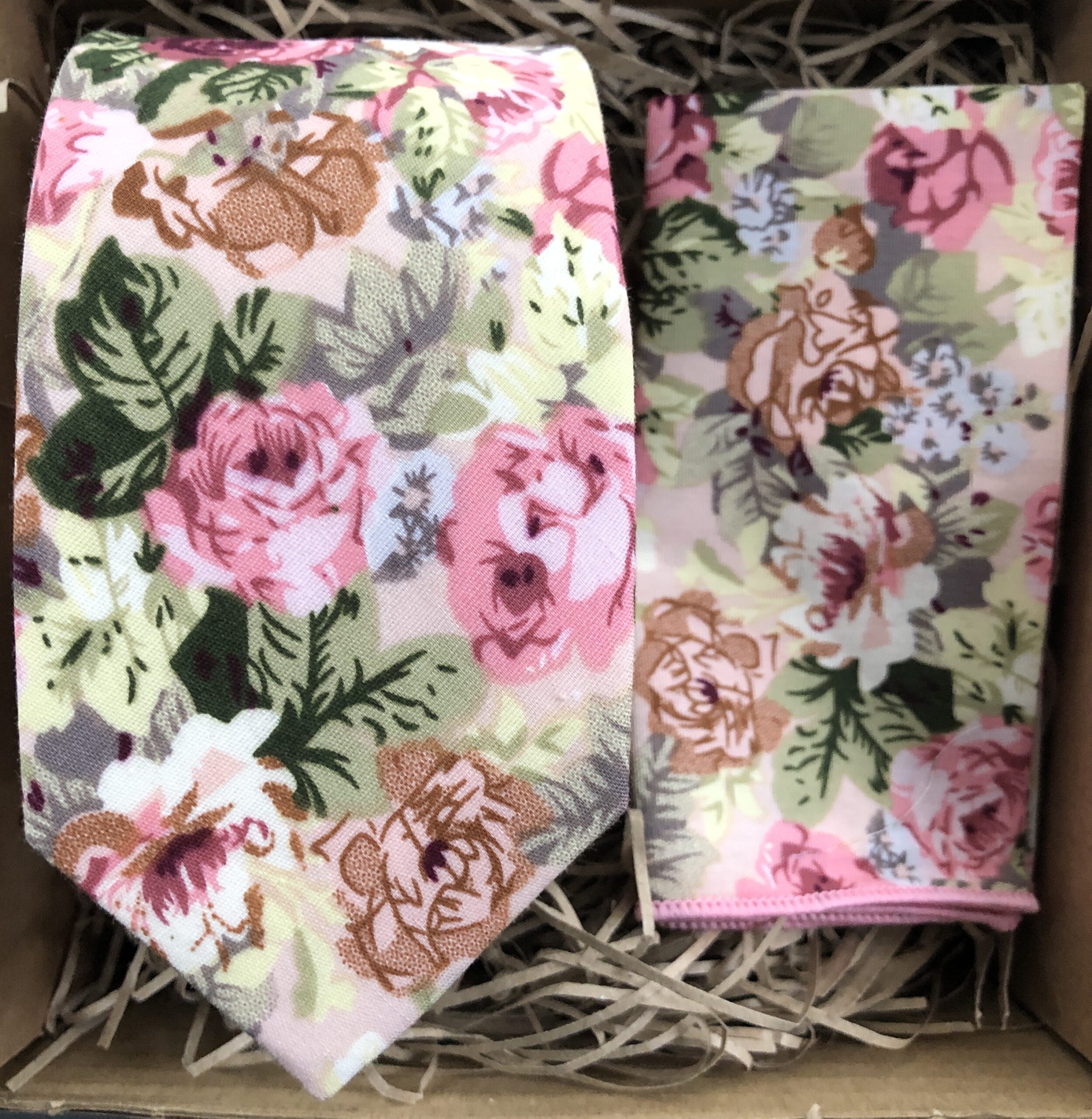 A photo of a pink floral cotton tie and pocket square