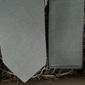 A photo of a sage green tie and pocket square in cotton