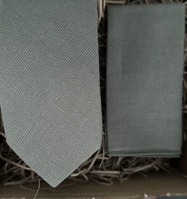 A photo of a sage green tie and pocket square in cotton