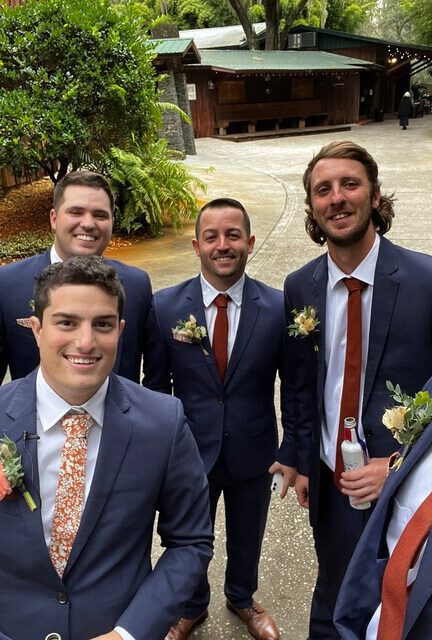 A photo of a groom and groomsmen wearing a floral tie and burnt orange tie