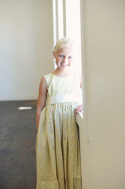 A photo of a young flower girl wearing a lemon yellow floral flower girl dress