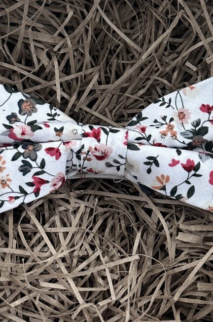 A photo of a pink and white floral bow tie that is pre-tied