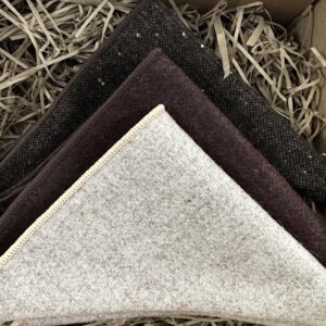 A photo of a trio of pocket squares in brown, cream and black flecked wool ideal as a gift for men