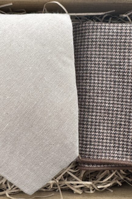 A photo of a beige cotton linen effect men's tie and a brown houndstooth pocket square set. Ideal for all occasions.