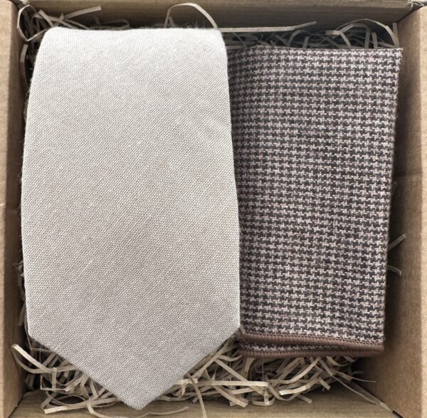 A photo of a beige cotton linen effect men's tie and a brown houndstooth pocket square set. Ideal for all occasions.