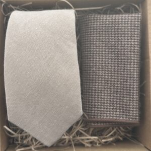 A photo of a beige cotton linen effect men's tie and a brown houndstooth pocket square set