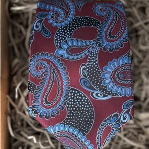 A photo of a paisley burgundy and blue men's tie