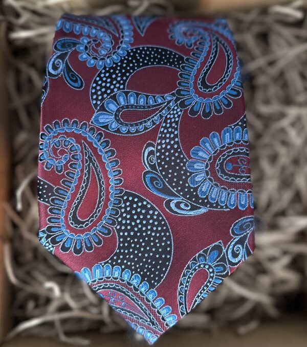 A photo of a paisley burgundy and blue men's tie