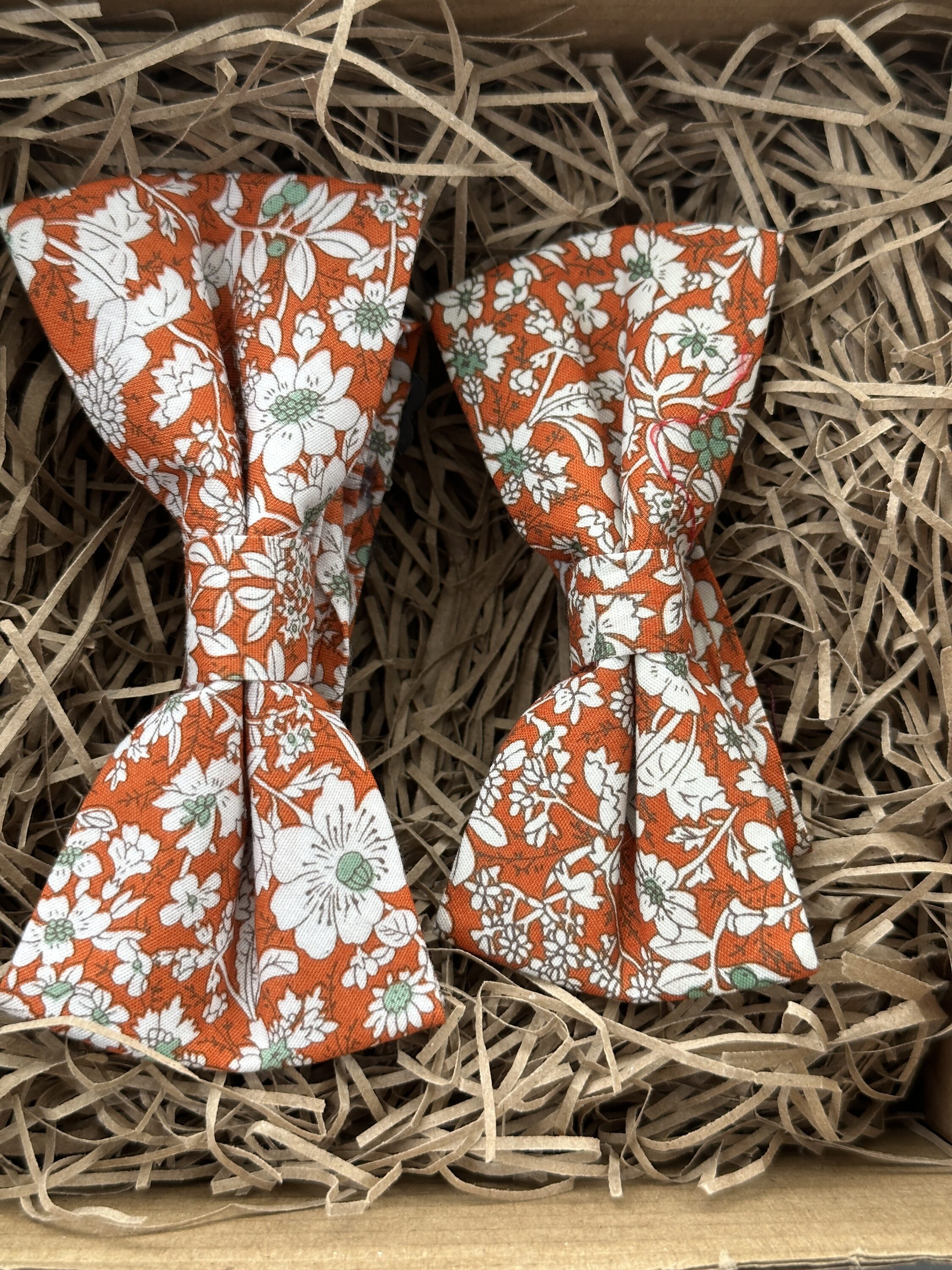 A photo of an adult and child sized orange floral bow tie set. Ideal for events where adult and child would like to match.