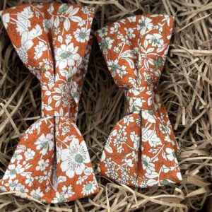 A photo of an adult and child sized orange floral bow tie set. Ideal for events where adult and child would like to match.