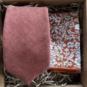 A photo of a terracotta brushed cotton men's tie and an orange floral pocket square. The tie set is ideal for all occasions and perfect as a man's gift as it comes gift wrapped.Ideal as groomsman gifts.