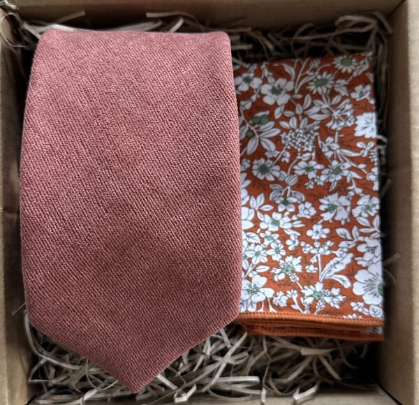 A photo of a terracotta brushed cotton men's tie and an orange floral pocket square. The tie set is ideal for all occasions and perfect as a man's gift as it comes gift wrapped.Ideal as groomsman gifts.