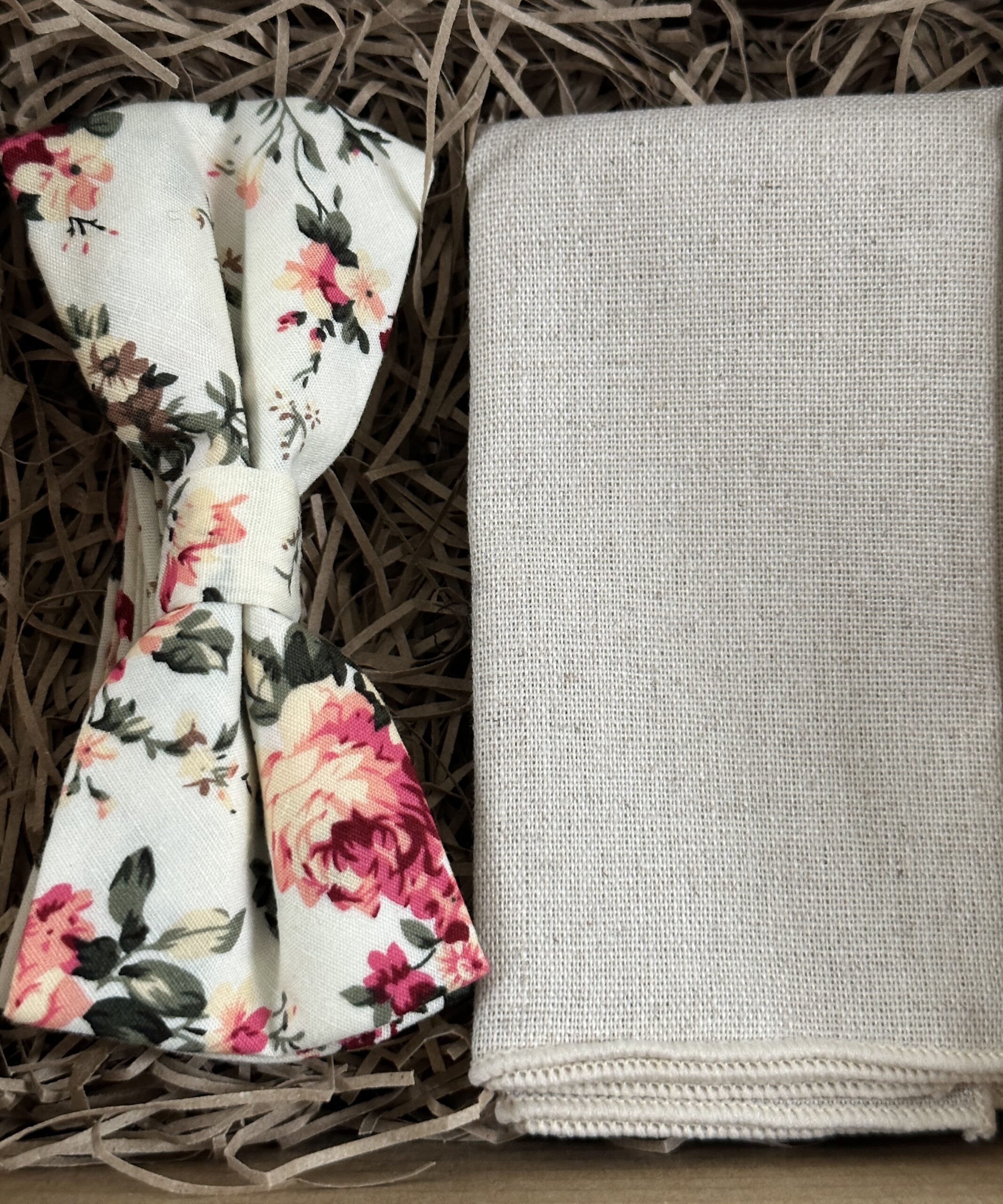 A photo of a pink floral cotton bow tie and a flax linen pocket square
