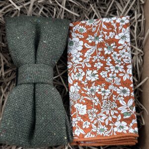 A photo of a moss green woo pre-tied bow tie and an orange floral pocket square