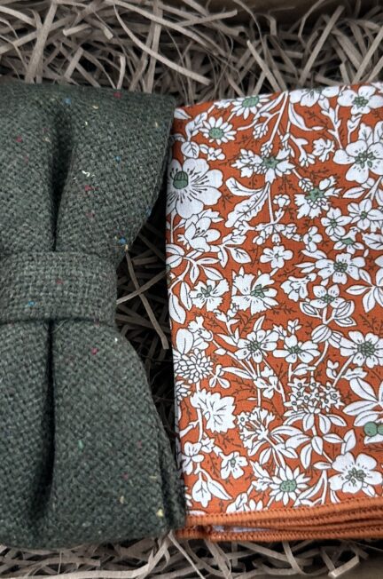 A photo of a moss green woo pre-tied bow tie and an orange floral pocket square