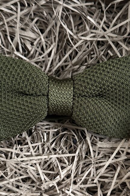 A photo of a green knitted bow tie with an elasticated strap
