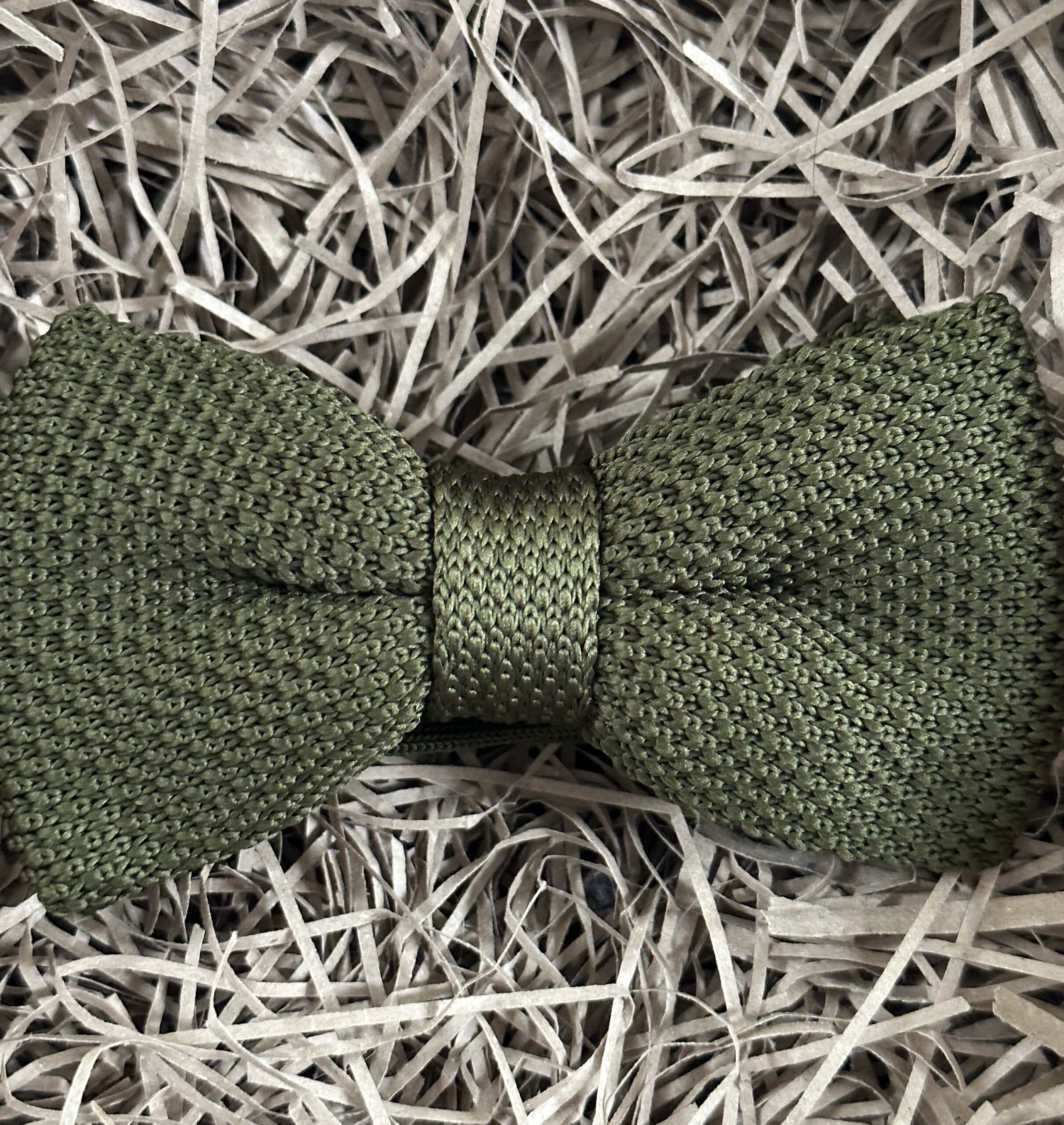 A photo of a green knitted bow tie with an elasticated strap