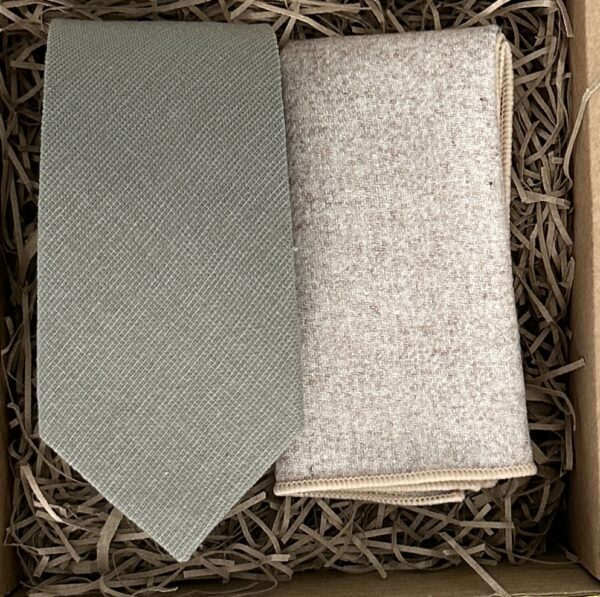 A photo of a sage green cotton tie and a cream wool pocket square. A perfect blend of textures.