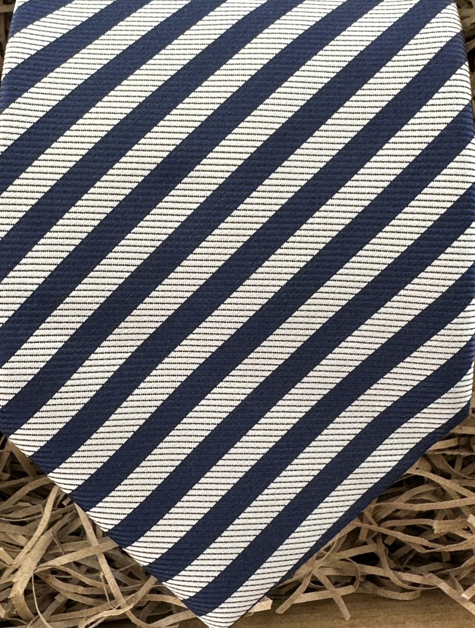 A photo of an 8 cm wide mens' necktie in a sliver and navy stripe.