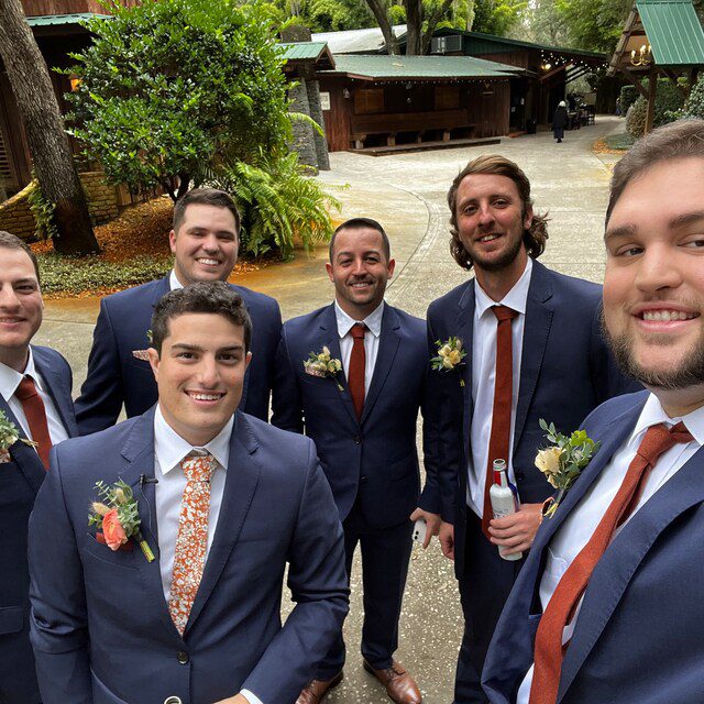 Groomsmen wearing a premium quality burnt orange tie and the groom in an orange floral tie.